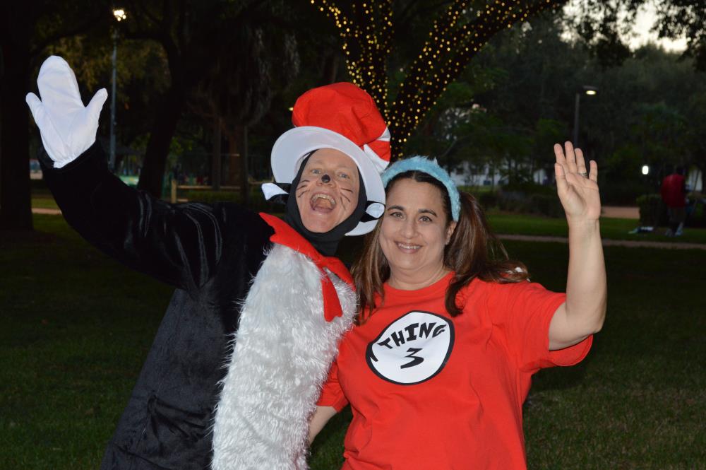 Woman dressed as the Cat in the Hat waves to camera with woman dressed as Thing 3